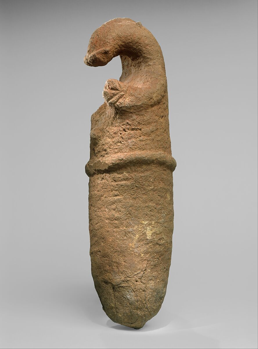 A tan colored stone in the shape of an animal with head at the top and a rounded end.