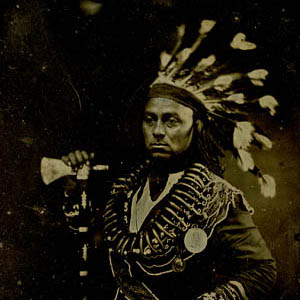 Thumbnail of a man in a native american headress holding a hatchet 