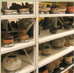 Color image of shelving with various artifacts, most of which are clay bowls or vessels